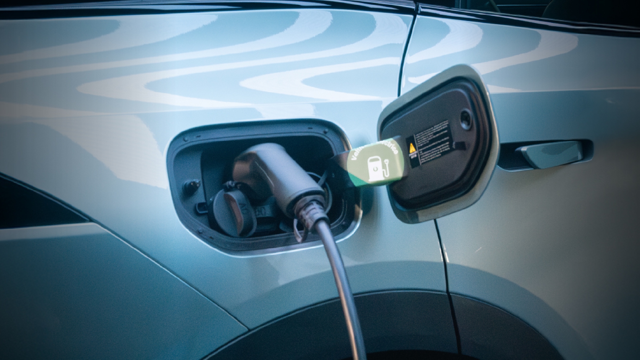 Vista cercana de auto eléctrico siendo conectado cargándose.